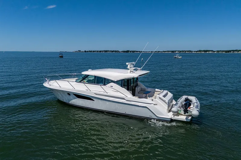  Yacht Photos Pics 2020 Tiara Yachts C44 Coupe cruising on open water under clear blue skies.