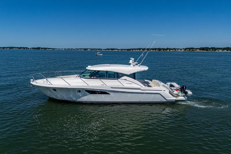  Yacht Photos Pics 2020 Tiara Yachts C44 Coupe cruising on open water under clear blue skies.