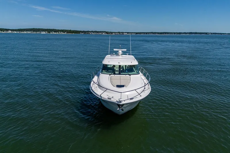  Yacht Photos Pics 2020 Tiara Yachts C44 Coupe cruising on open water under clear blue skies.