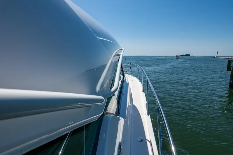  Yacht Photos Pics 2020 Tiara Yachts C44 Coupe cruising on open water under clear blue skies.
