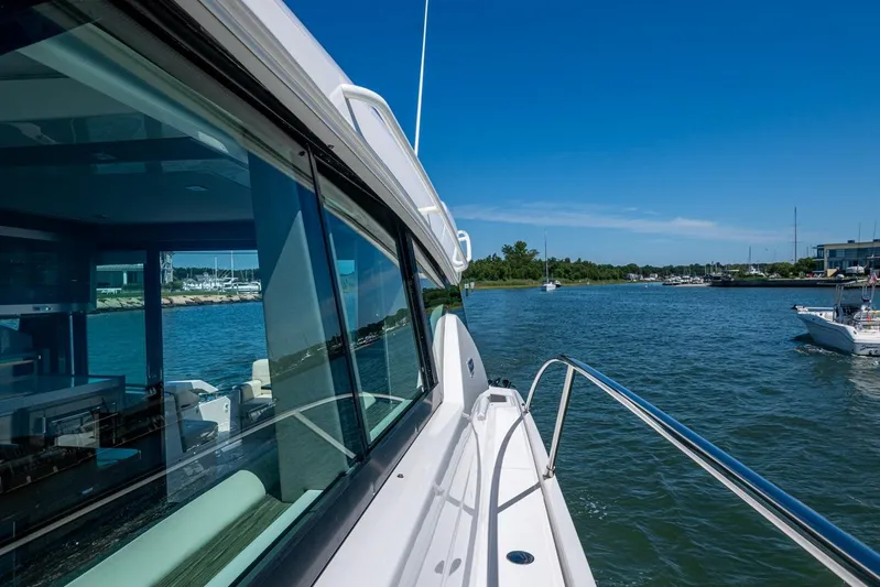  Yacht Photos Pics 2020 Tiara Yachts C44 Coupe cruising on a sunny day near a marina.