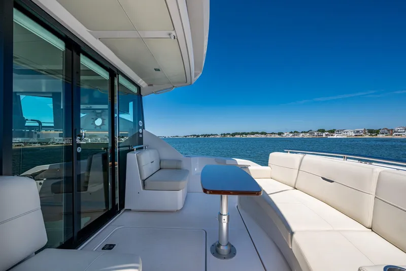  Yacht Photos Pics 2020 Tiara Yachts C44 Coupe deck with seating, overlooking serene waters and shoreline.