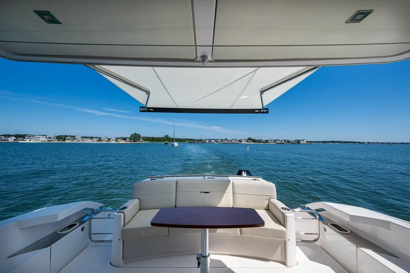  Yacht Photos Pics 2020 Tiara Yachts C44 Coupe, rear deck view, overlooking serene waters and distant shoreline.