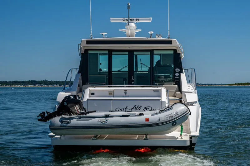  Yacht Photos Pics 2020 Tiara Yachts C44 Coupe with dinghy on water, rear view.