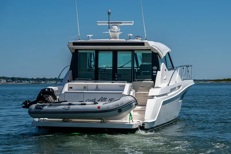  Yacht Photos Pics 2020 Tiara Yachts C44 Coupe cruising on open water with inflatable boat attached.