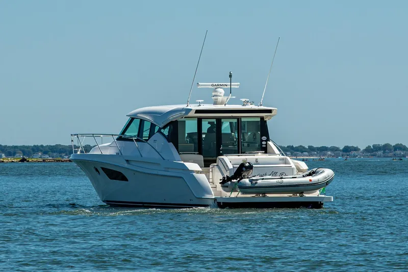  Yacht Photos Pics 2020 Tiara Yachts C44 Coupe cruising on open water with inflatable boat attached.
