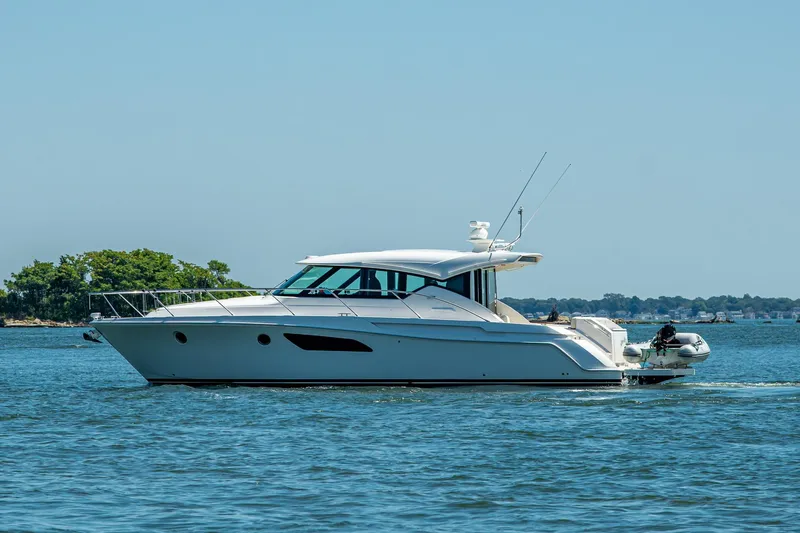  Yacht Photos Pics 2020 Tiara Yachts C44 Coupe cruising on a sunny day, surrounded by calm waters.