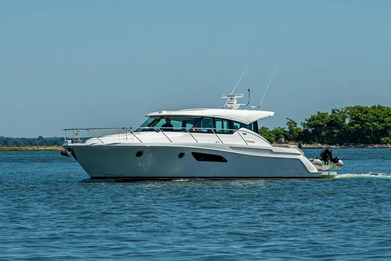  Yacht Photos Pics 2020 Tiara Yachts C44 Coupe cruising on calm waters, clear sky background.