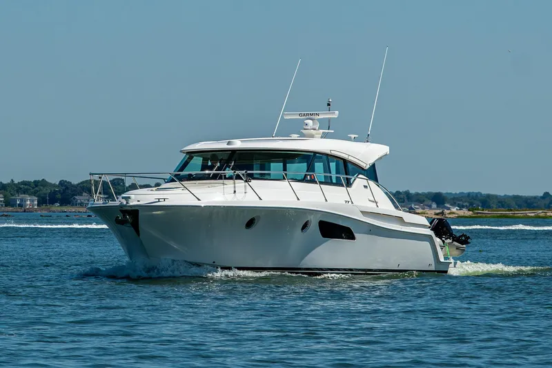  Yacht Photos Pics 2020 Tiara Yachts C44 Coupe cruising on open water under clear skies.