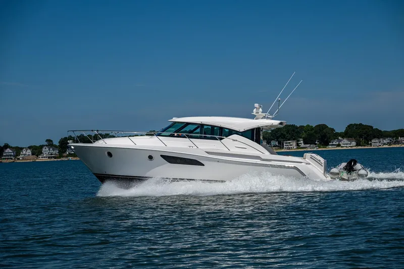  Yacht Photos Pics 2020 Tiara Yachts C44 Coupe cruising on a sunny day near the shoreline.