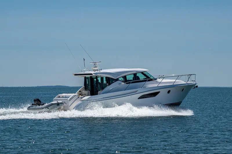  Yacht Photos Pics 2020 Tiara Yachts C44 Coupe cruising on open water under clear skies.