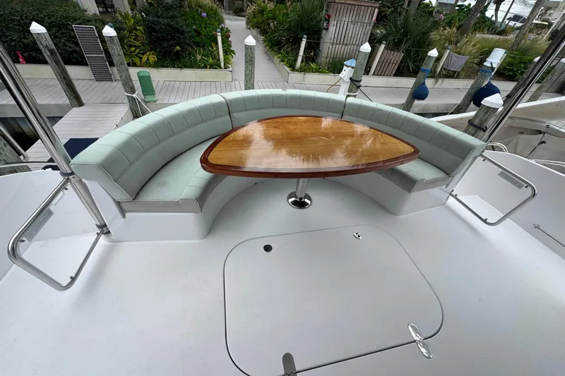 Elsewhere Yacht Photos Pics Curved seating area with wooden table on 2013 Hatteras 60 Motor Yacht deck.