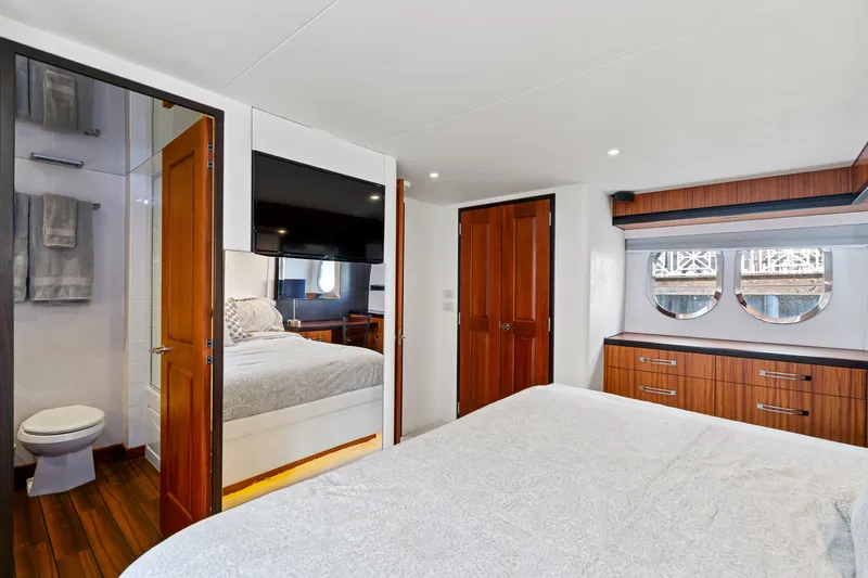 Elsewhere Yacht Photos Pics Luxurious bedroom and bathroom in 2013 Hatteras 60 Motor Yacht, featuring elegant wood finishes.