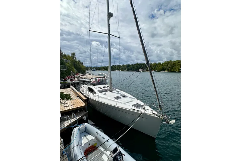 Porte Du Soleil Yacht Photos Pics 2015 Jeanneau Sun Odyssey 50 DS sailboat docked on a scenic lake.