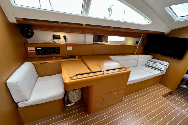 Porte Du Soleil Yacht Photos Pics Luxurious interior of 2015 Jeanneau Sun Odyssey 50 DS sailboat with wood finish and seating.