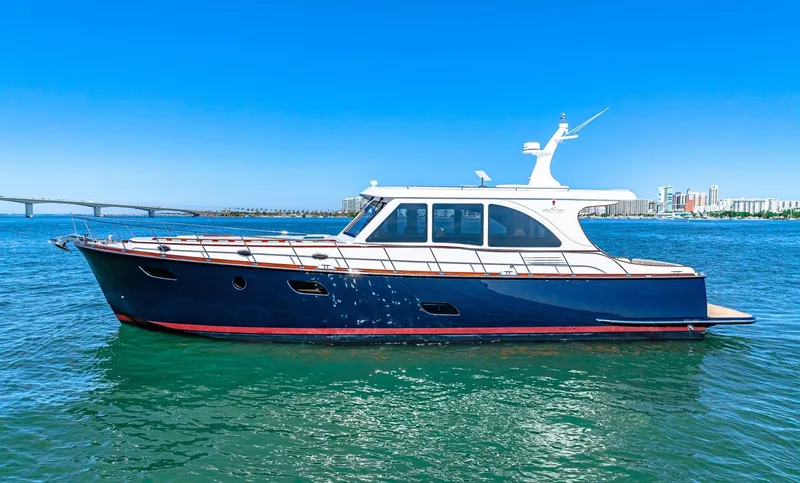 Island Girl III Yacht Photos Pics 2024 Vicem 62 Classic yacht on clear blue water, bridge and cityscape in background.