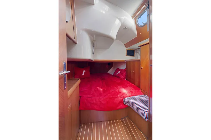 Crazy Horse Yacht Photos Pics Cozy cabin interior of 2001 Jeanneau Sun Odyssey 52.2 with red bedding and wooden accents.
