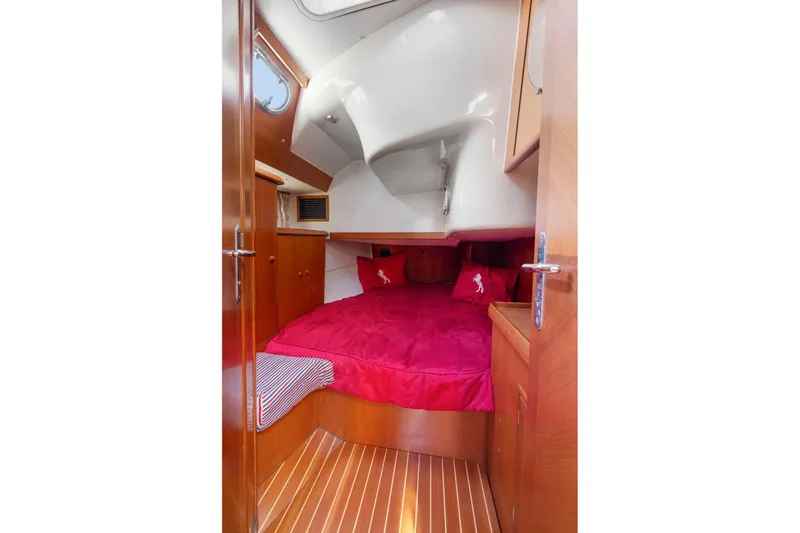 Crazy Horse Yacht Photos Pics Cozy cabin interior of 2001 Jeanneau Sun Odyssey 52.2 with red bedding and wooden finish.