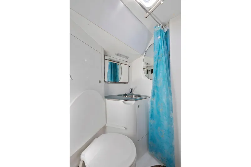 Crazy Horse Yacht Photos Pics Compact bathroom in 2001 Jeanneau Sun Odyssey 52.2 yacht with blue shower curtain.