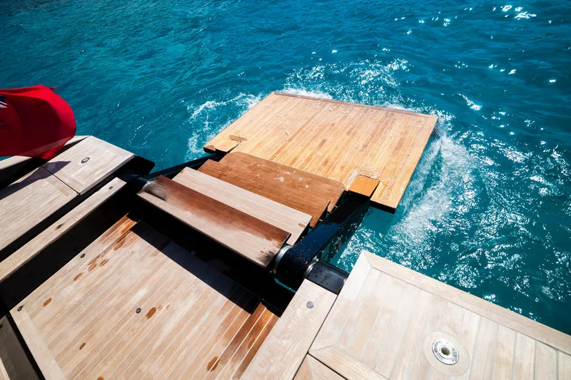 Dragon Yacht Photos Pics Wooden swim platform on 2017 Windy SR52 Blackbird yacht, extending into clear blue water.