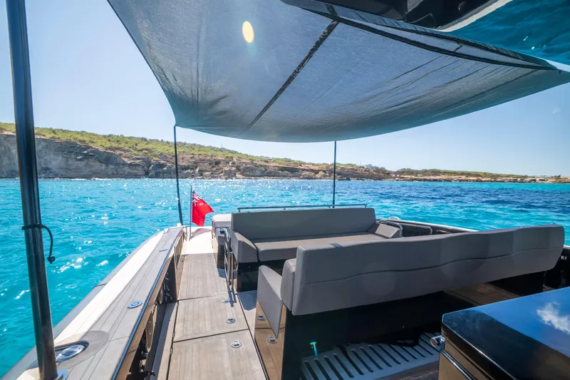 Dragon Yacht Photos Pics 2017 Windy SR52 Blackbird yacht with shaded seating, overlooking turquoise waters and rocky coastline.