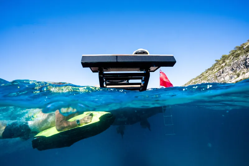 Dragon Yacht Photos Pics Underwater view of 2017 Windy SR52 Blackbird yacht with swimmer and vibrant blue sea.