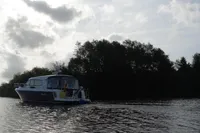 Nimbus 405 Coupé 2022 cruising on a serene river with trees in the background.