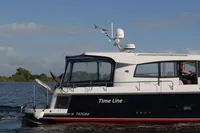 2022 Nimbus 405 Coupé boat cruising on a calm river under a clear blue sky.