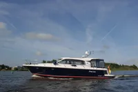 2022 Nimbus 405 Coupé yacht cruising on a calm lake under a clear blue sky.
