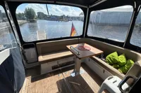 Interior of 2022 Nimbus 405 Coupé boat with seating, table, and scenic water view.