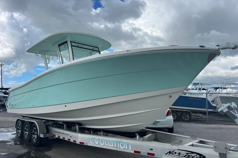  Yacht Photos Pics 2020 Robalo R302 Center Console boat on trailer under cloudy sky.