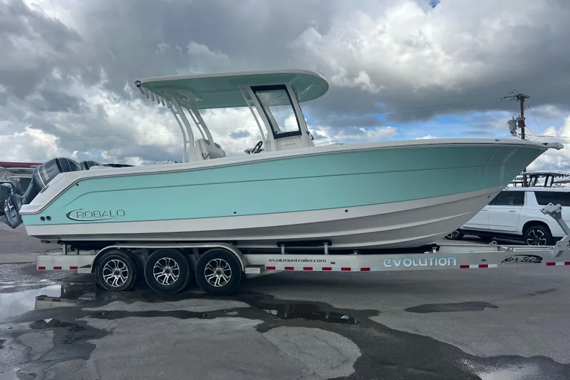  Yacht Photos Pics 2020 Robalo R302 Center Console boat on trailer under cloudy sky.