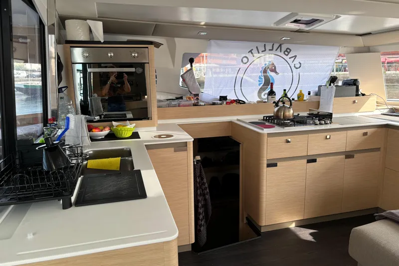 Cabalito De Mar Yacht Photos Pics Modern kitchen interior of 2024 Fountaine Pajot Catamaran Elba 45 with appliances and wooden cabinetry.