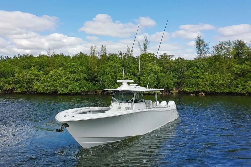 Yacht Photos Pics 2026 Yellowfin 42 Offshore boat cruising on a serene waterway with lush greenery.