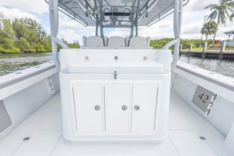  Yacht Photos Pics 2026 Yellowfin 42 Offshore boat interior with seating and storage, docked by lush greenery.