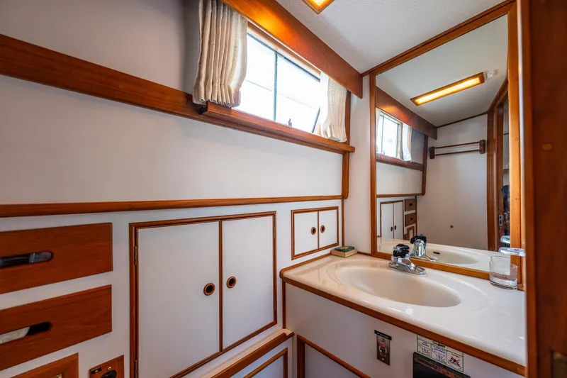 Voyageur Yacht Photos Pics 1995 Grand Banks Aft Cabin 42 Classic bathroom with sink, mirror, and wooden cabinetry.