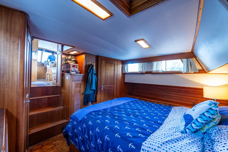 Voyageur Yacht Photos Pics Grand Banks Aft Cabin 42 Classic 1995 bedroom with wooden interior and blue bedding.