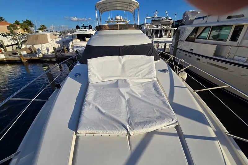Solitude Yacht Photos Pics 1997 Sunseeker Manhattan 48 yacht with sunbed, docked at marina under clear blue sky.