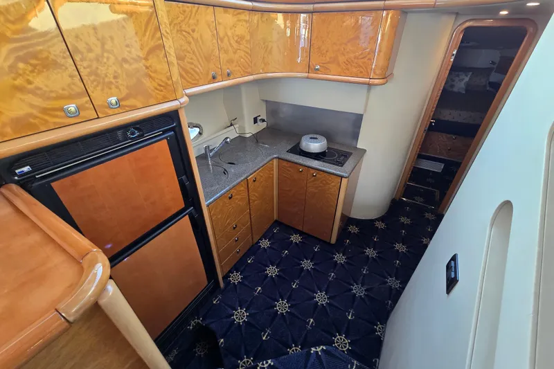 Solitude Yacht Photos Pics Interior of 1997 Sunseeker Manhattan 48 yacht kitchen with wood cabinets and nautical carpet.