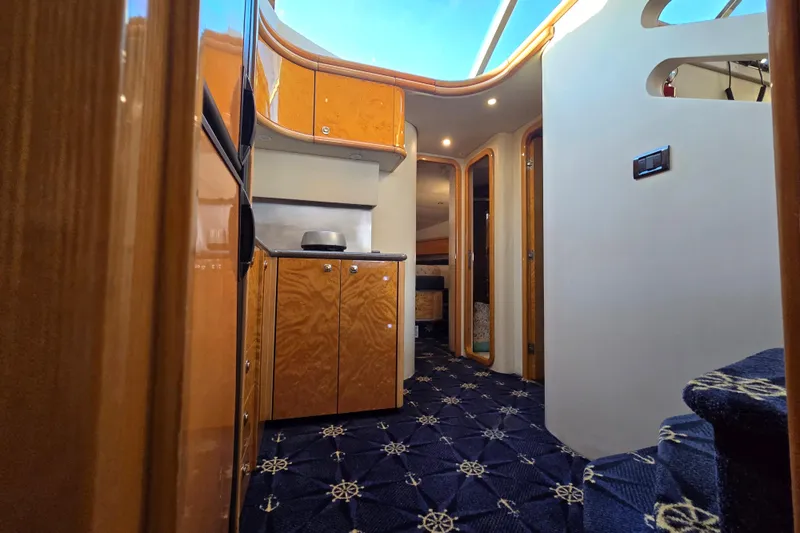 Solitude Yacht Photos Pics Interior of 1997 Sunseeker Manhattan 48 yacht with wooden cabinetry and nautical-themed carpet.