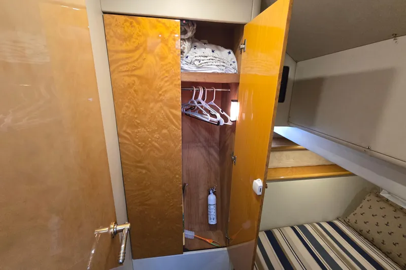 Solitude Yacht Photos Pics Sunseeker Manhattan 48 yacht interior, 1997, showing a wooden wardrobe with hangers and bedding.
