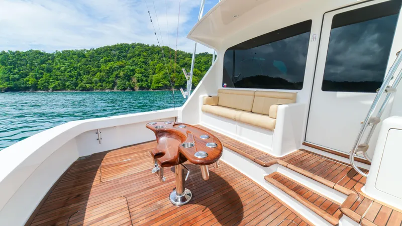 Manudito Yacht Photos Pics 2009 Viking 50C yacht with teak deck and fishing chair, cruising near lush green island.