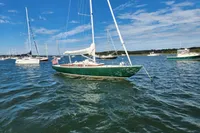 Sailboat Rustler 33 (2017) anchored in a sunny harbor with other boats.