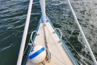 Bow of a 2017 Rustler 33 sailboat with buoy on calm water.
