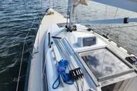 Sailing yacht Rustler 33, 2017 model, deck view with ropes and hatch, on calm water.