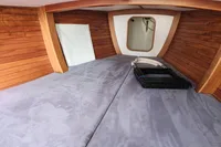 Cozy interior of 2017 Rustler 33 sailboat with wooden paneling and soft bedding.