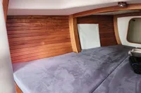 Cozy cabin interior of 2017 Rustler 33 sailboat with wooden paneling and plush bedding.