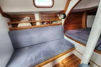 Cozy interior of a 2017 Rustler 33 sailboat with wooden accents and blue cushions.