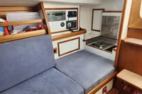 Cozy interior of 2017 Rustler 33 sailboat with blue seating and compact kitchen area.