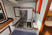 Compact galley in 2017 Rustler 33 yacht with stove, sink, and wooden accents.